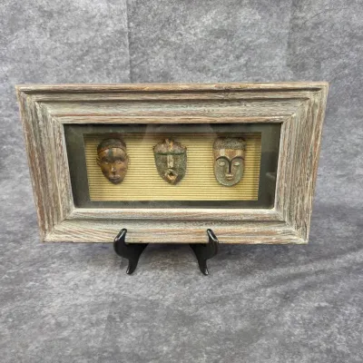Framed shadowbox displaying three miniature African-style masks, set in a rustic, weathered wood frame.