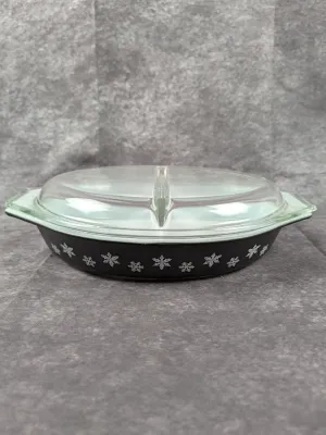 Vintage Pyrex divided serving dish in black with a white snowflake pattern, complete with its clear glass lid.