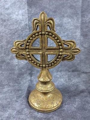 Ornate standing brass cross featuring fleur-de-lis accents and a beaded circular frame, set on a round pediment base.