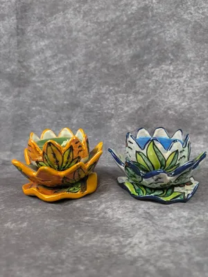 Pair of hand-painted ceramic lotus-shaped candle holders, one in warm orange and yellow tones and the other in cool blue and green hues.