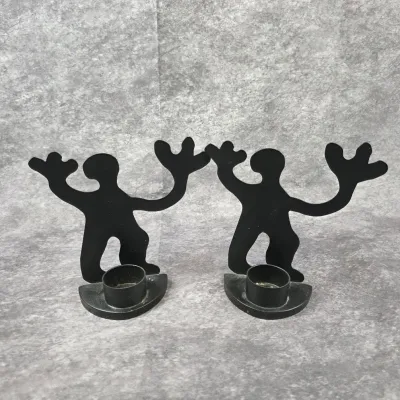 Pair of Keith Haring style black metal silhouette candle holders, featuring dancing figures with outstretched arms.