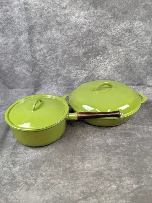 Vintage Dru Holland avocado green enameled cast iron cookware, including a saucepan with a wooden handle and a covered skillet, circa 1960s.