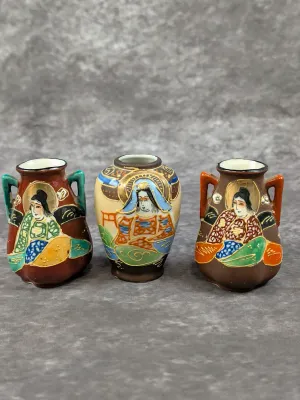 Trio of vintage Japanese Satsuma-style miniature bud vases, featuring hand-painted geisha and deity figures with raised moriage details.