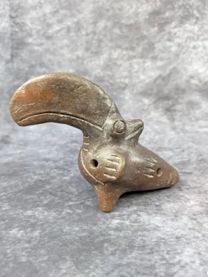 Pre-Columbian style clay ocarina shaped like a bird with a large beak, featuring incised details and a tripod base.