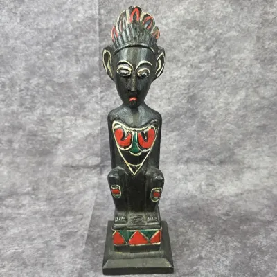 Hand-carved dark wood African-style tribal figurine featuring painted red and green accents on a square pedestal base.