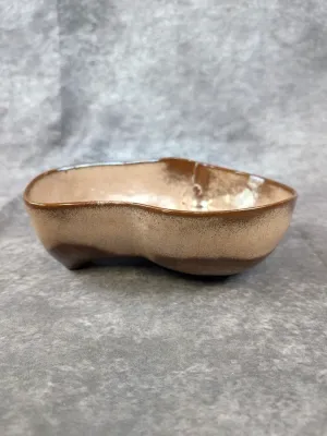 Handcrafted studio pottery dish featuring an organic kidney-bean shape with a two-tone brown and tan speckled glaze.