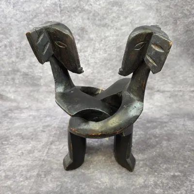 Hand-carved dark wood African sculpture depicting two stylized figures in an embrace, showing some surface wear and age.
