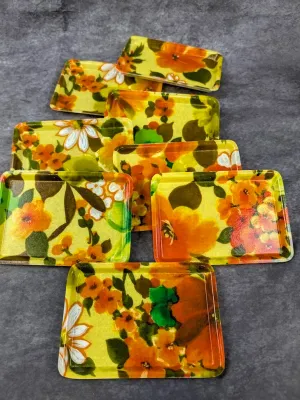 Set of vintage 1970s fiberglass snack trays featuring a bright yellow and orange floral power pattern.