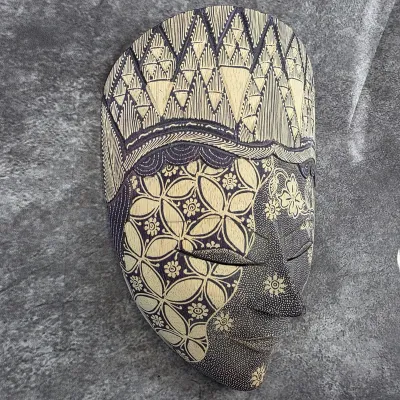 Hand-carved Indonesian batik wooden mask, featuring intricate geometric and floral patterns in a traditional style.
