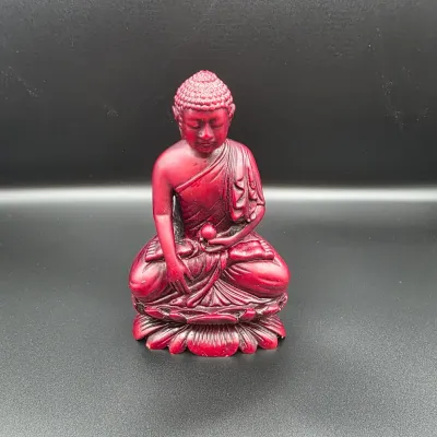Red carved cinnabar-style resin Buddha figurine seated in a meditative lotus position on a pedestal base.