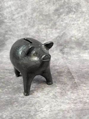 Vintage black clay pig-shaped coin bank, likely a traditional Mexican Barro Negro piece, showing minor surface wear.