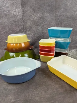 Collection of vintage Pyrex colorful glass cookware and refrigerator dishes, including a primary-color stack, oval casserole dishes, and...