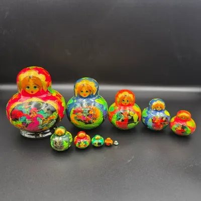 Set of 10 hand-painted Russian Matryoshka nesting dolls featuring colorful folk art scenes and gold accents against a dark background.