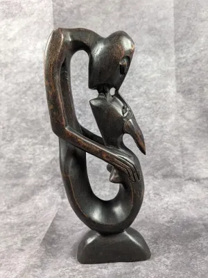 Hand-carved dark wood abstract figure sculpture featuring intertwined forms, standing on an integrated base.