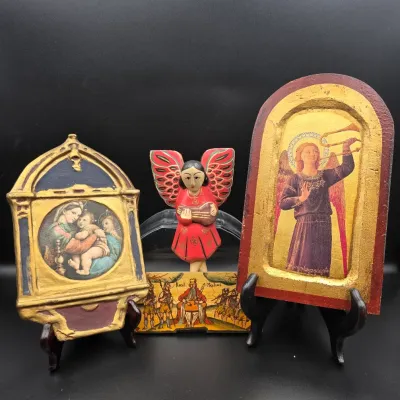 Collection of folk art and religious decorative pieces, including a carved wooden angel figure, painted icon-style plaques with gilt...