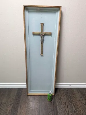 Vintage framed crucifix shadow box featuring a wooden cross with a metal corpus of Jesus, mounted on a light blue fabric backing in a...