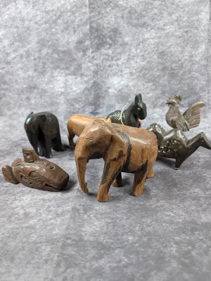 Collection of small hand-carved wooden animal figurines, including elephants, a horse, a bird, and a Pacific Northwest Indigenous style...