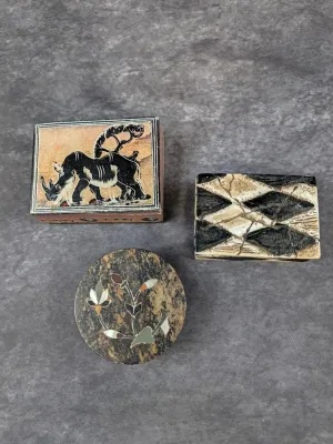Trio of small decorative trinket boxes, including a rectangular box with a rhinoceros illustration, a textured black and white...
