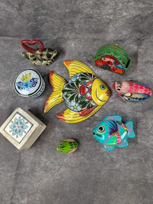 Collection of hand-painted Mexican folk art pottery and wooden items, including fish figurines, a small trinket box, and a coaster set.