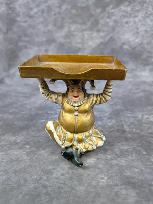 Vintage painted metal jester figurine holding a gold-toned tray, featuring detailed gold and white attire with a whimsical expression.