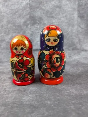 Two hand-painted wooden Russian matryoshka nesting dolls featuring colorful floral motifs and stylized facial details.