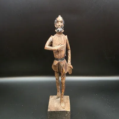 Hand-carved wooden statue of Don Quixote standing on a square base, featuring intricate carved details and a natural wood finish.
