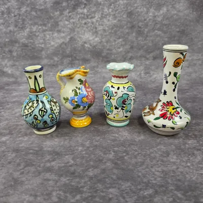 Collection of four vintage hand-painted Italian Deruta-style miniature ceramic vases, featuring colorful floral and geometric motifs.