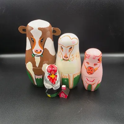 Hand-painted wooden farm animal nesting doll set, including a cow, sheep, pig, rooster, and tiny barn figurine.
