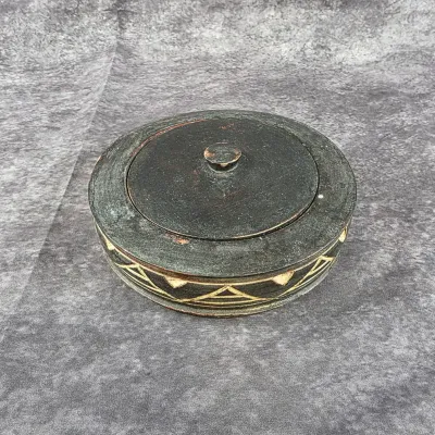 Vintage hand-carved wooden lidded box with a dark, distressed finish and geometric tribal-style patterns around the base.