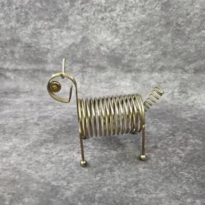 Vintage mid-century brass wire dog letter holder, featuring a coiled spring body, stick legs, and a curly tail.