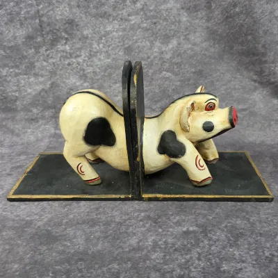 Vintage hand-carved and painted wooden pig bookends, featuring a whimsical black and white spotted pig split in half.