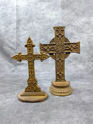 Pair of decorative cast iron standing crosses with intricate relief detailing and a weathered, rustic finish.