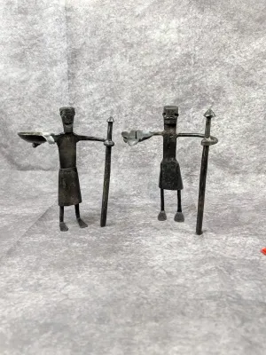 Pair of vintage hand-forged iron warrior figurines, each holding a staff and a small bowl, featuring a rustic, folk art style.