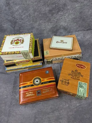 Collection of vintage wooden and cardboard cigar boxes, including brands like Macanudo, Chesterfield, Cuesta-Rey, and Perdomo Double Aged...