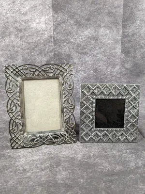 Pair of ornate silver-tone metal picture frames, including a filigree scrollwork rectangular frame and a square geometric embossed frame.