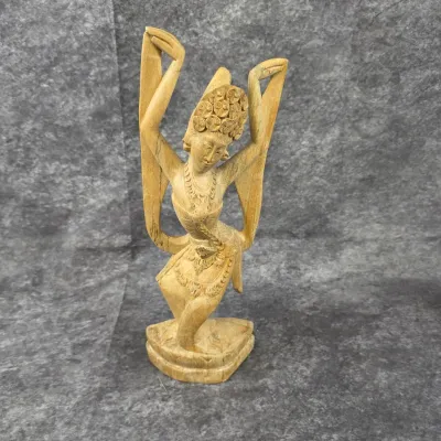 Hand-carved Balinese wooden sculpture depicting a traditional dancer in a dynamic pose, featuring intricate details on the headdress and...