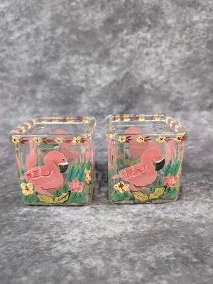 Pair of small, square glass votive holders featuring hand-painted pink flamingos, tropical foliage, and yellow flowers.