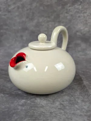 Vintage ceramic teapot featuring a whimsical face design with red lips forming the spout and a crackle glaze finish.