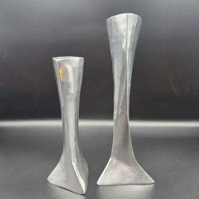 Pair of modern pewter or polished aluminum candlestick holders in varied heights, featuring sculptural twisted triangular stems.
