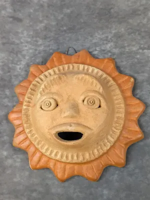 Hand-crafted Mexican terracotta sun face wall plaque with a wire loop for hanging.