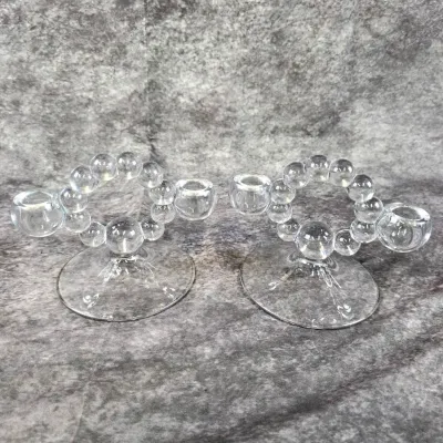Pair of vintage clear glass double candle holders, featuring a distinctive beaded ring design on circular bases.