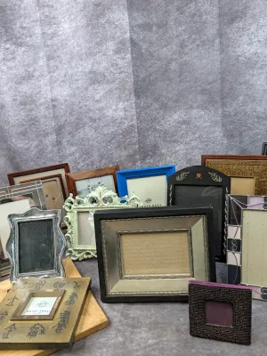 Collection of assorted small picture frames in various styles and finishes, including wood, metal, painted, and beaded designs.