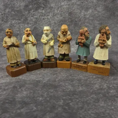 Collection of six vintage hand-carved wooden medical figurines, depicting various doctors and medical professionals in a caricature style.