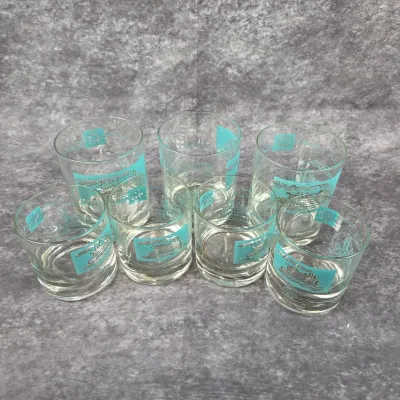 Set of seven mid-century lowball glasses featuring turquoise and silver-tone illustrations of paddle steamers and riverboats.
