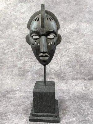 Hand-carved dark wood African-style mask sculpture, mounted on a matching wooden display stand.