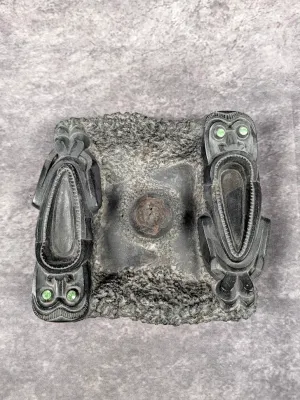 Indigenous-style carved argillite or dark stone ash tray featuring carved tiki figures with inlaid green eyes.