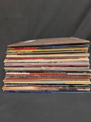 Stack of vintage vinyl LP records, featuring artists such as Linda Ronstadt, Rickie Lee Jones, and The Alan Parsons Project, showing some...