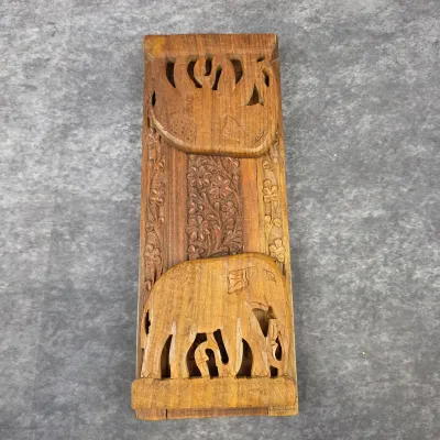 Hand-carved wooden book stand featuring intricate floral patterns and two elephant figures, shown in its folded flat position.