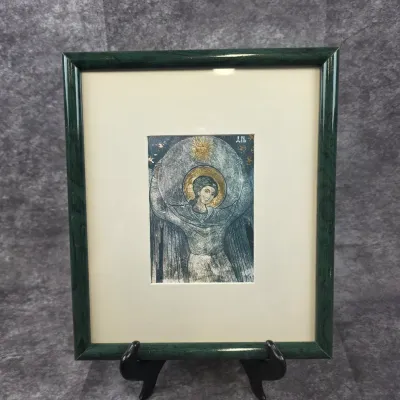 Framed religious art print depicting an angel with a golden halo, housed in a matted green frame.