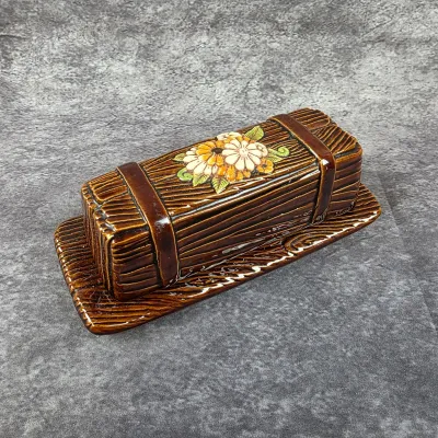 Vintage ceramic butter dish with a faux-wood grain texture and a floral motif on the lid, likely from the 1970s.